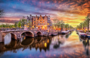 Panoramic view of the historic city center of Amsterdam. Traditional houses and bridges of Amsterdam town. A romantic evening and a bright reflection of houses in the water